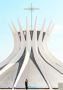 woman standing in front of gray concrete structure with cross thumbnail