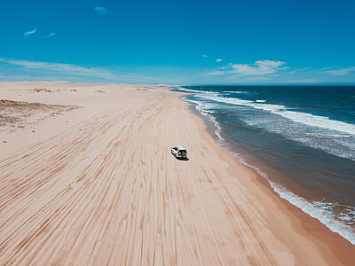 aerial view of white vehicle on seashore during daytime thumbnail