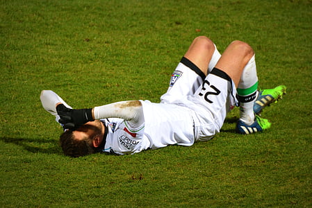 man in soccer jersey laying on green grass thumbnail