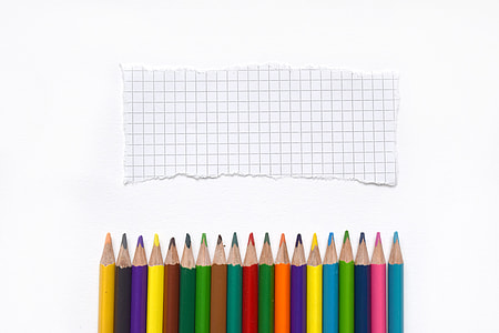 assorted-color color pencil lined up in front of ripped grid paper thumbnail