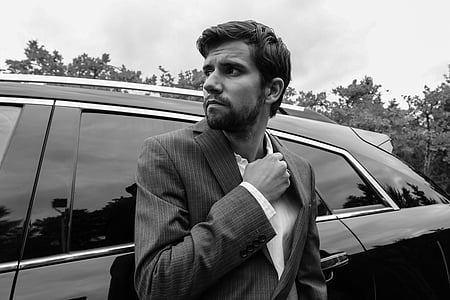 man in black suit beside car thumbnail