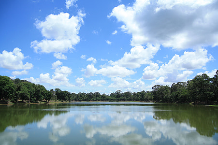 body of water between trees under clear blue sky thumbnail