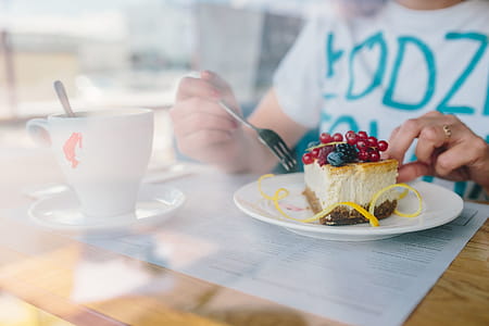 Woman Enjoying Cheese Cake and a Coffee with Fruits in a Cafeteria thumbnail