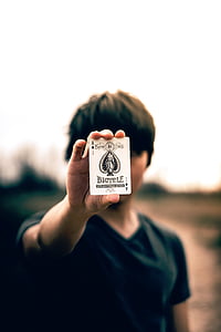 selective focus photography of person holding Bicycle ace of spade card thumbnail