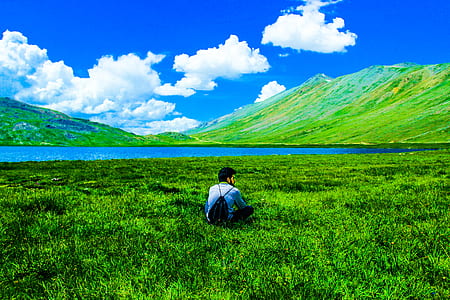 Boy Sitting on Green Grass Field thumbnail