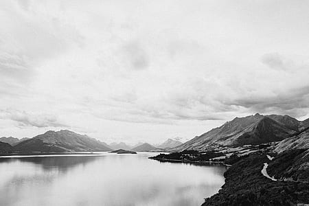 grayscale phography of body of water near mountain thumbnail