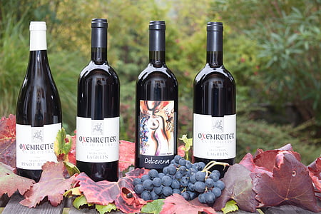 four wine bottles near grapes during daytime photography thumbnail