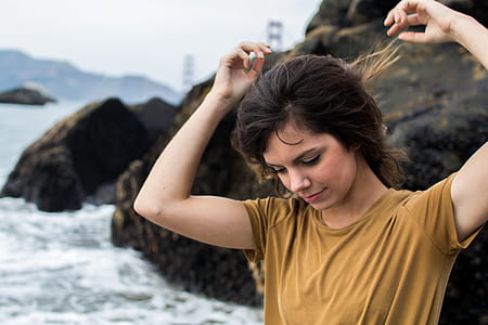 woman fixing her hair near rocks and beach thumbnail