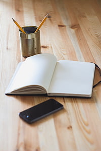can of two pencils beside book and iPhone on table thumbnail