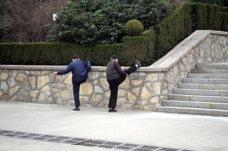 two men leaning their foot on wall near stairs thumbnail