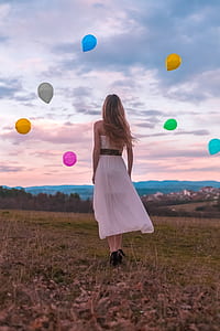 woman standing on ground while looking at multicolored ballons thumbnail