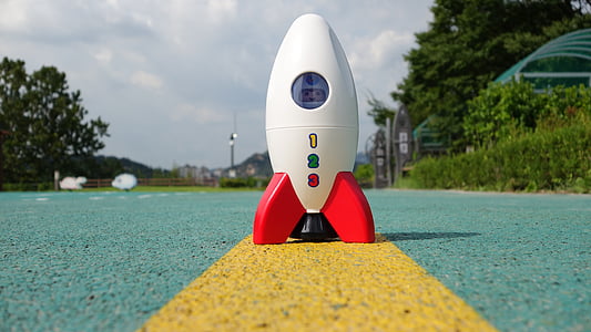 white toy rocket on cement pavement thumbnail