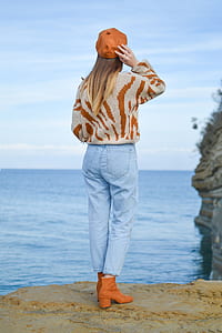 woman standing on cliff overlooking body of water at daytime thumbnail