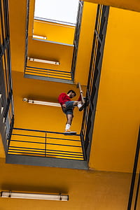 man wearing red sweater standing on black metal handrail stair thumbnail