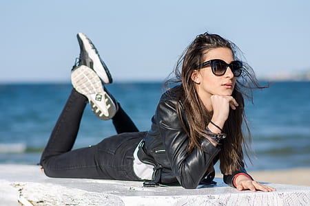 woman lying on white concrete platform near body of water during daytime thumbnail