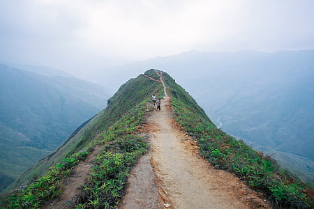 people walking on pathway above hill thumbnail