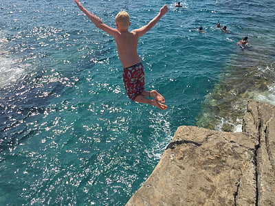 jumping boy on cliff during daytime thumbnail