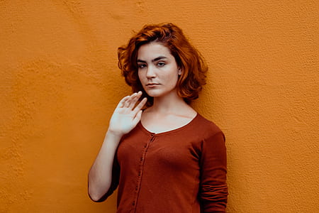 woman leaning against orange painted wall during daytime thumbnail