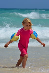 girl in pink wet suit near sea at daytime thumbnail