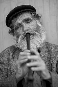 greyscale photo of bearded man playing flute thumbnail
