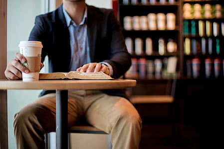 man sitting touching book and holding cup thumbnail