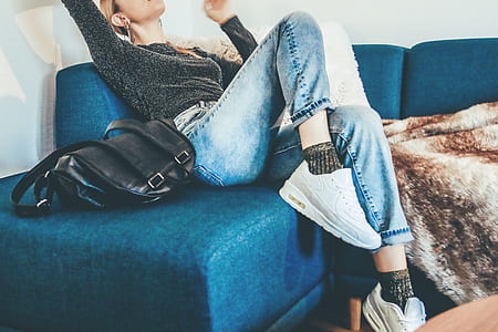 woman wearing black blue denim jeans sitting on the sofa thumbnail