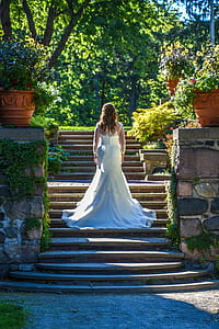 woman wearing wedding gown walking on stairs beside plants during daytime thumbnail
