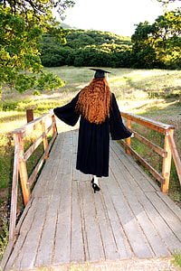 woman in black graduation dress on brown wooden bridge during daytime thumbnail