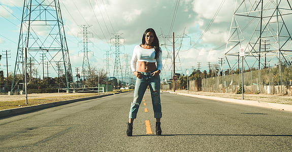 woman in white long-sleeved crop top standing in middle of gray road thumbnail