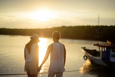 man and woman holding hand beside body of water during daytime thumbnail