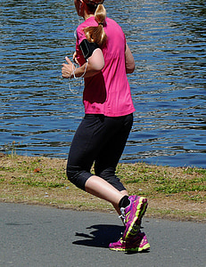 woman jogging near body of water during daytime thumbnail