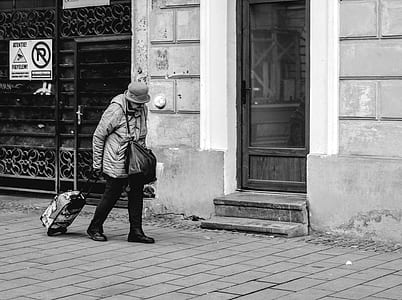 greyscale photo of woman pulling her luggage outdoors thumbnail