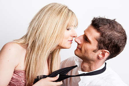 woman holding man's necktie while facing each other thumbnail
