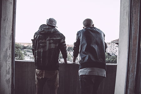 two men wearing jackets standing on balcony thumbnail