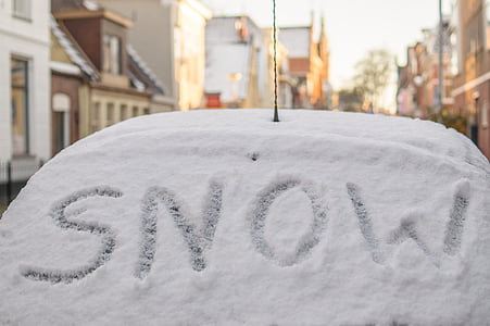 white snow-covered car between houses thumbnail