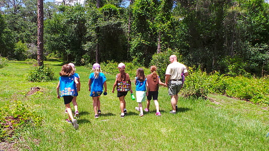 group of children and man walks on green grass thumbnail