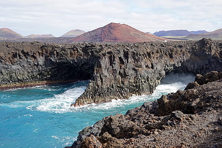 body of water beside black rocky cliff thumbnail