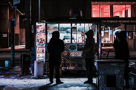 three person standing in front of food stall at nighttime thumbnail