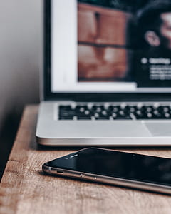 space gray iPhone 6 beside MacBook Pro turned on thumbnail