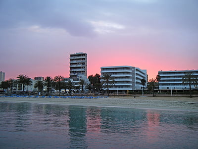 white buildings beside seashore during golden hour photo thumbnail