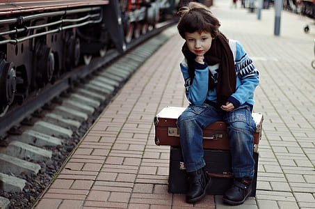 boy in blue sweater and jeans seating near train thumbnail