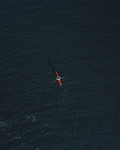 aerial photography of person riding red kayak on green body of water thumbnail