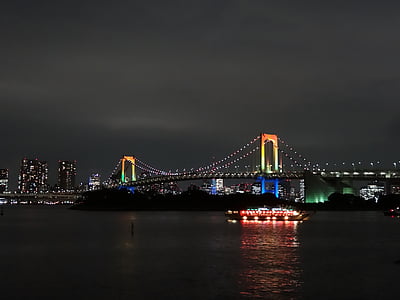 ferry maneuvering under bridge during night time thumbnail
