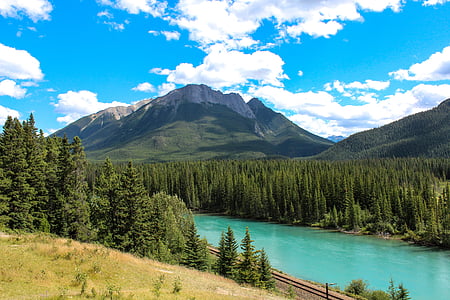 river near mountain under white clouds blue skies daytime thumbnail