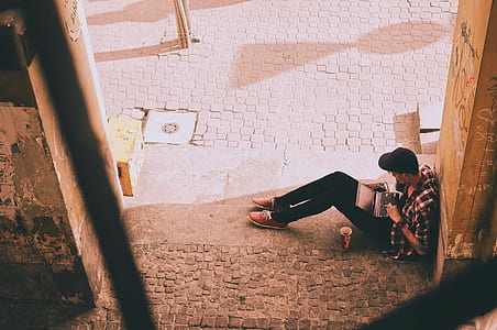 high-angle photography of man sitting and leaning on wall while using laptop thumbnail