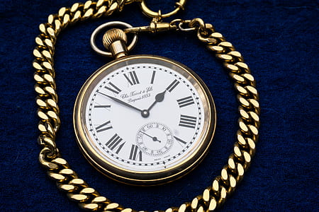 round white analog pocket watch with gold-colored frame on blue textile thumbnail