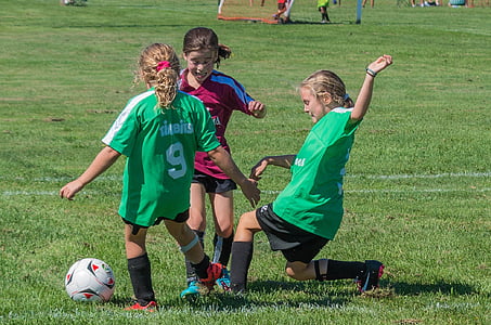 several girls chasing white soccer ball in a football game on field during daytime thumbnail