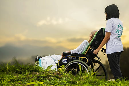 woman holding wheelchair with person during daytime thumbnail