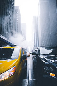 yellow taxi cab beside black SUV between high-rise building thumbnail