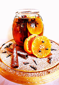 filled jar with red liquid, sliced orange, and star anise while 2 slices of oranges by jar and sticks of chocolate thumbnail